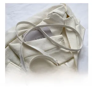 Detail of white crocodile embossed texture on a crossbody bag with metal chain trim