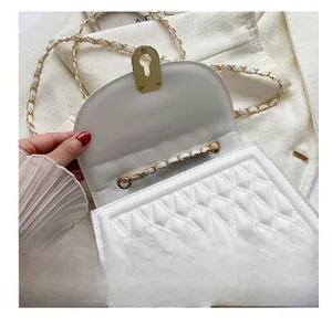 Detail of white quilted crossbody bag with gold chain strap and twist lock closure