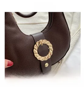 Detail view of lychee texture leather and golden wavy metal ring buckle on the coffee bag
