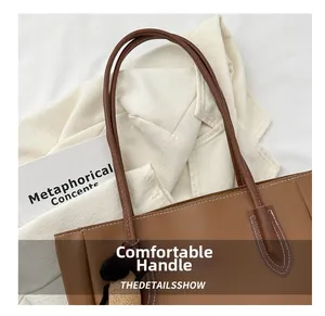 Detail of a brown leather tote bag showing comfortable slim handles and a cute bear charm
