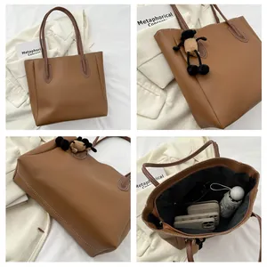 Macro detail of brown leather tote showing white contrast stitching and plush lamb charm