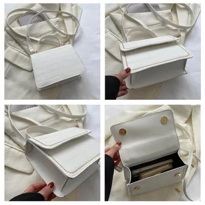 Detail of white crocodile pattern shoulder bag with yellow stitching and gold magnetic clasp