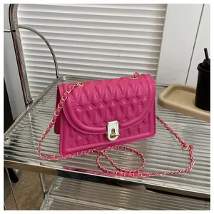 Detail of fuchsia quilted handbag featuring a gold chain strap and enamel twist lock