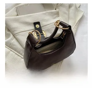 Detail of dark brown lychee pattern leather handbag with gold metal ring handle and interior space