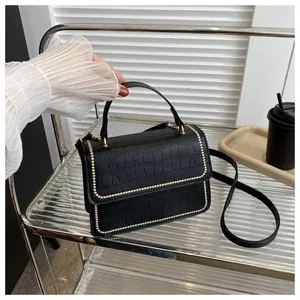 Close-up of black crocodile embossed leather shoulder bag with gold rivet detailing