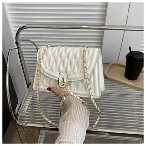 Detail of white quilted crossbody bag with gold-tone lock and chain strap
