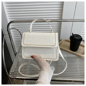 Detail of white faux crocodile texture handbag with decorative gold bead trim