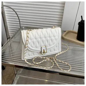 Detail of white quilted crossbody bag with gold twist lock and metal chain strap