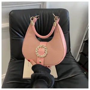 Detailed view of pink lychee leather half-moon handbag with gold hardware decoration