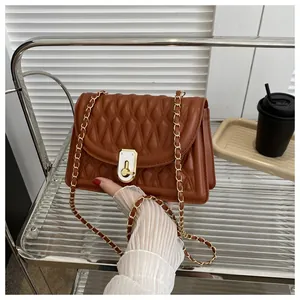 Macro detail of brown quilted leather texture and gold chain strap on a small crossbody bag