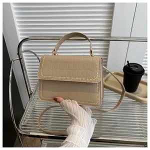 Close-up of beige crocodile texture shoulder bag featuring beaded trim edge details