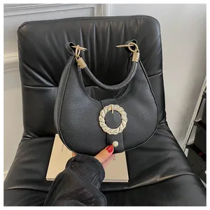 Detail of black lychee grain half-moon handbag with gold circular wavy buckle