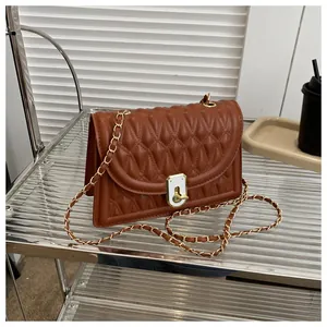 Close-up of caramel brown quilted small square bag with gold chain strap and turn-lock