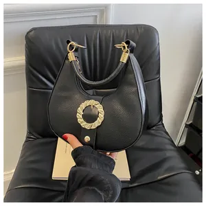 Close-up of black lychee grain leather hobo bag with bold gold buckle and metallic details