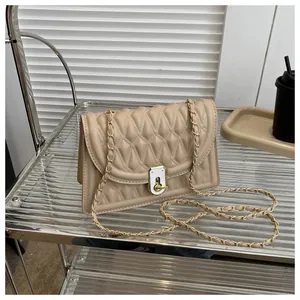 Detailed close-up of quilted beige crossbody bag with gold chain strap and turn-lock