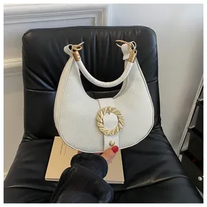 Detail of white crescent handbag with lychee pattern leather and gold spiral buckle