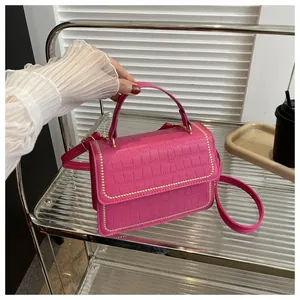Detailed macro of hot pink faux leather bag featuring embossed crocodile pattern and gold studs