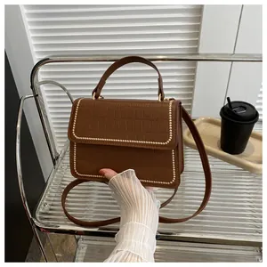 Detailed macro view of brown crocodile texture leather bag with gold rivet accents