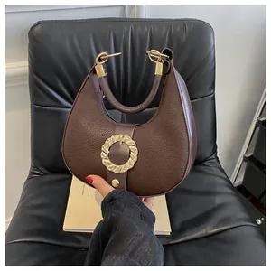 Detail view of coffee brown crescent bag with litchi grain leather and gold ring buckle