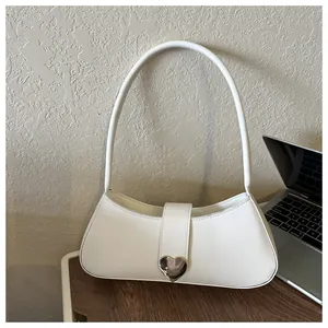 Detail of white hobo bag featuring a silver heart buckle on a leather strap