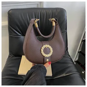 Detailed macro view of dark brown crescent bag with litchi grain texture and gold clasp