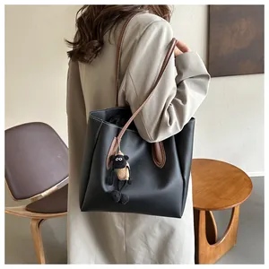 Detail of black tote bag with brown straps and cute sheep charm on model