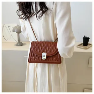 Detailed shot of brown quilted leather crossbody bag with gold chain and cylinder clasp