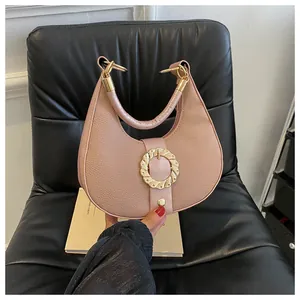 Detail of pink crescent bag with lychee texture leather and gold wave buckle