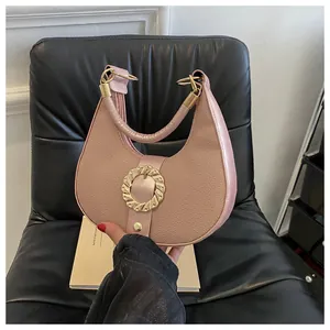 Detail of pink crescent hobo bag with lychee texture and large golden buckle ornament