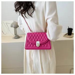 Close-up of rose red quilted crossbody bag with gold twist lock and chain strap detail