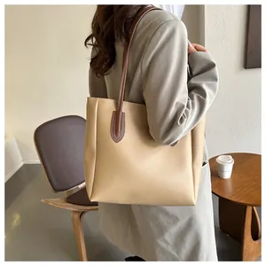 Detail showing the beige tote bag with brown straps styled on a model in a blazer