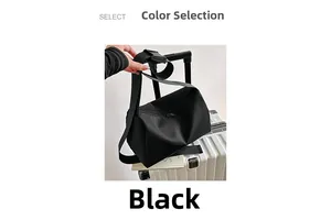 Large black Oxford cloth tote bag with wide strap placed on a white suitcase