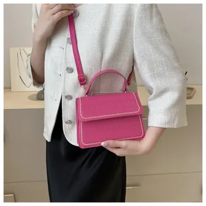 Detail of pink crocodile pattern square bag with gold rivet studs and elegant handle