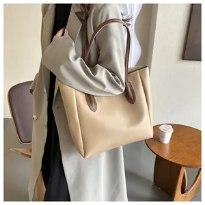 Side view of large minimalist beige tote bag with brown straps worn by female model