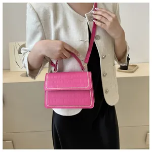 Close-up of rose pink crocodile embossed leather bag with silver rivet studs details