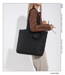 Detail der schwarzen Stepptasche mit Rautenmuster und rundem Mini-Münztäschchen-Anhänger