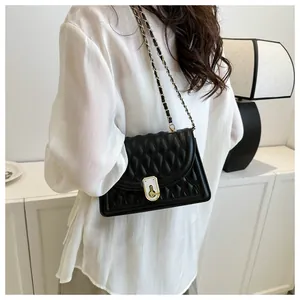 Detail of classic black quilted shoulder bag featuring gold lock and metal chain strap