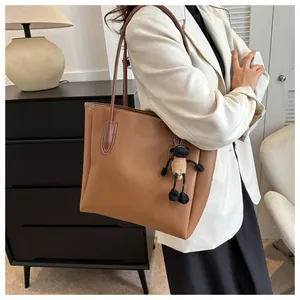 Detailed view of brown leather tote bag with a cute lamb charm on a white blazer model