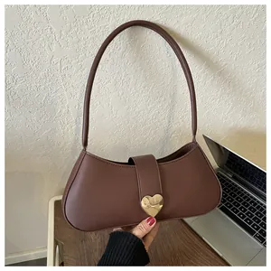 Close-up of a dark brown leather underarm bag with a large metallic heart buckle