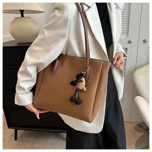 Brown leather tote bag detail with white contrast stitching and a plush lamb keychain