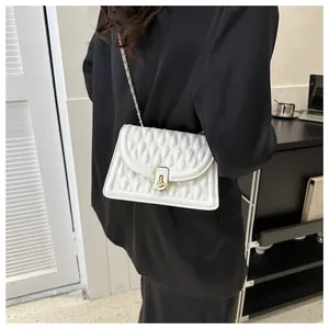 Detail of white quilted leather crossbody bag with golden clasp and chain strap