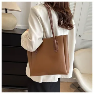 Detailed side view of large brown faux leather tote bag with white contrast stitching