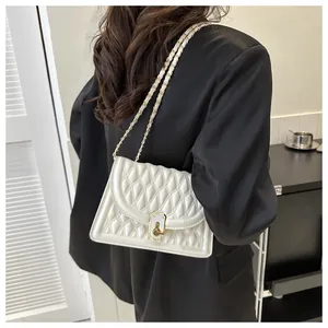 Close-up of white quilted crossbody bag with gold chain strap and metal lock detail
