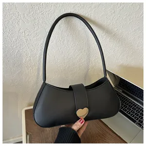 Close-up of black PU leather underarm bag featuring a polished gold heart-shaped metal clasp