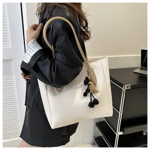 Detail of off-white tote bag with pleated side seams and cute sheep plush pendant charm