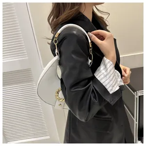 Detail of white half-moon shoulder bag with lychee grain texture and gold twist buckle