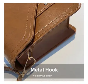 Detail of caramel brown leather shoulder bag featuring golden metal hook and stitching