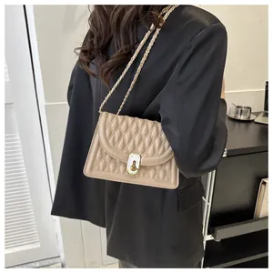 Detail of beige quilted crossbody bag with gold chain strap and metal lock closure