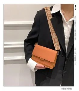 Model wearing a small orange flap crossbody bag with a vintage wide jacquard strap