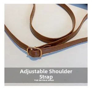 Detail of adjustable brown synthetic leather shoulder strap with gold buckle and stitching